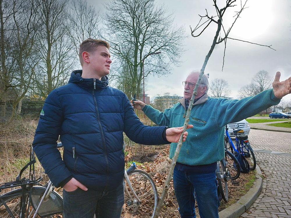 Frits Doornenbal doceert leerling Aeres over fruitbomen